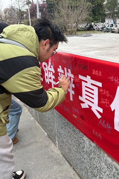 图三 志愿者在横幅前签字.jpg