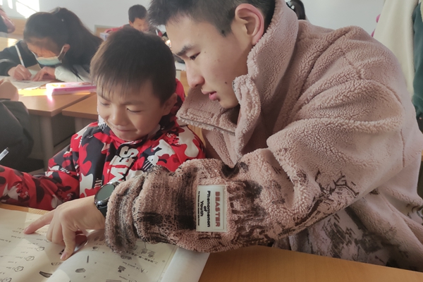 cb97e5cac22942a78c66e1338b32c4dc.jpg 志愿者辅导小朋友完成作业.jpg